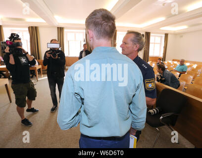 Kempten, Germany. 01st Aug, 2019. A man (M) is led by policemen into a courtroom of the district court. Because the 22-year-old wanted to take revenge on his ex-girlfriend, who had separated a few weeks ago, the young man is said to have brutally beaten to death his son, who was only eight months old. Since today (01.08.2019) the father has to answer for murder before the district court of Kempten. Credit: Karl-Josef Hildenbrand/dpa/Alamy Live News Stock Photo