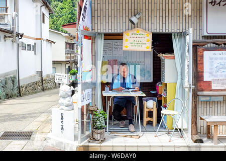 A man working in a tiny tourist office in Dorogawa Onsen, Nara Prefecture, Japan. Stock Photo