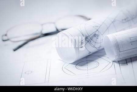 Rolls of drawings with glasses in the background Stock Photo