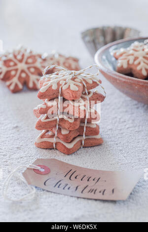 Stack of homemade biscuits with snowflake icing, tied with string and Christmas gift labels Stock Photo