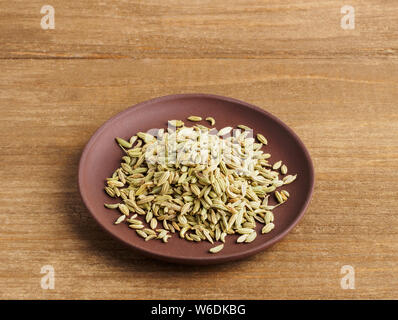 Fennel seeds (Foeniculum vulgare) in a clay plate on a wooden background Stock Photo
