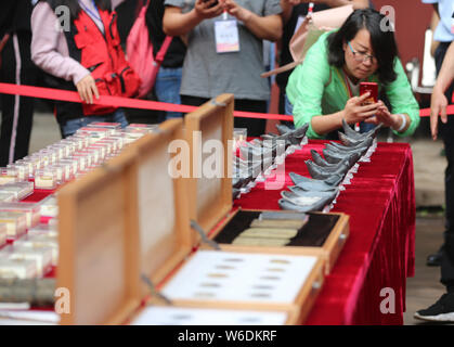 A Chinese journalist takes photos of silver ingots unearthed from the sunken boats owned by peasant leader Zhang Xianzhong (Chang Hsien-chung) of the Stock Photo