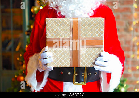 Santa Claus secretly putting gift boxes under the Christmas tree. Xmas Stock Photo