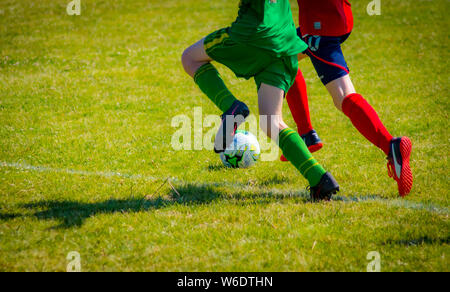 Two opposing players chasing a football. The athletes in the image are 14 year old boy soccer players. This shot catches them both in action. Stock Photo