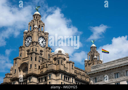 The LBGT flag flying over the Liver Building at Pier Head next to the Mersey in Liverpool, UK Stock Photo