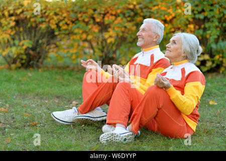 Portrait of fit senior couple meditating in autumn park Stock Photo
