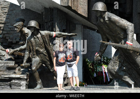 Warsaw Poland - Thursday 1st August - A Polish couple stand proudly in front of the Warsaw Uprising monument in Warsaw as Poland commemorates the 75th Anniversary of the Warsaw Uprising ( Powstanie Warszawskie ) against the occupying German Army on 1st August 1944 - the Warsaw Uprising resistance fighters of the Home Army ( Armia Krajowa  - AK ) struggled on for 63 days against the Nazi forces before capitulation as the advancing Soviet Army waited across the nearby River Vistula. Photo Steven May / Alamy Live News Stock Photo