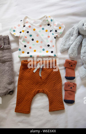 A cute baby outfit layed out on a white sheet background Stock Photo