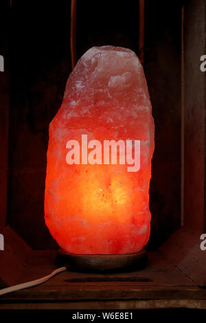 Himalayan salt lamp on wooden table illuminated Stock Photo