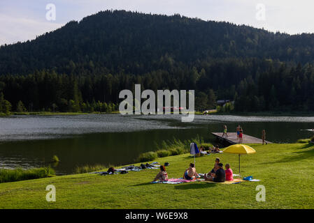 People seen sunbathing at the shores of Wildsee lake in Seefeld.Tirol is a western Austrian state located in the Alps known for its ski resorts, trekking trails and historic locations. Stock Photo