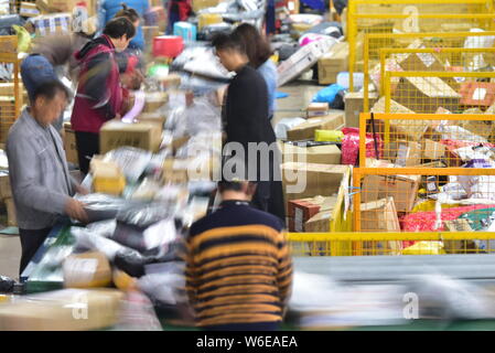 --FILE--Chinese workers sort out piles of parcels, most of which are from Singles Day online shopping, at a distribution center in Neijiang city, sout Stock Photo