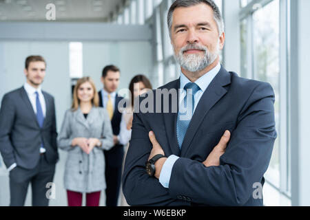 Businessteam in office, Happy Senior Businessman in His Office is standing in front of their team. Stock Photo