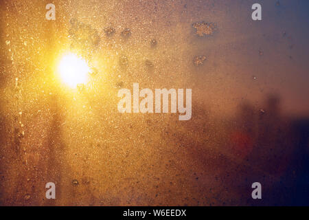 Stunning vintage amber blue sunrise light with blurred cityscape skyline bokeh background through frozen window glass. Soft focus Stock Photo