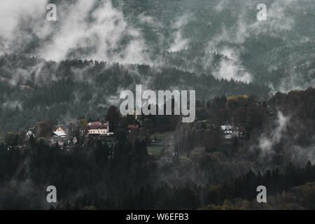 Deadpan dark misty rainy morning landscape with the sand rocky montains in Czech Saxon Switzerland in autumn colors. Stock Photo