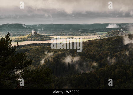 Deadpan dark misty rainy morning landscape with the sand rocky montains in Czech Saxon Switzerland in autumn colors. Stock Photo