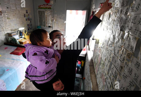 Two-year-old Chinese prodigy named 'He Meiqi' reads characters posted on the wall accompanied by her father at home in Hefei city, east China's Anhui Stock Photo