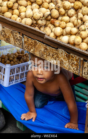 A Little Boy Hides Under A Potato Stall, Carbon Market, Cebu City, Cebu, The Philippines Stock Photo