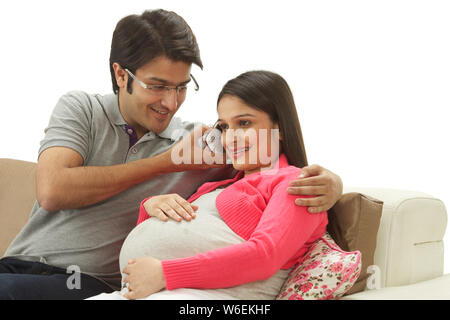 Pregnant woman talking on mobile phone with her husband holding it Stock Photo