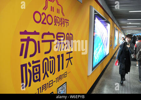 --FILE--Pedestrians walk past an advertisement of Suning.com, the online shopping site of home appliance chain Suning, for the 11.11 online shopping f Stock Photo