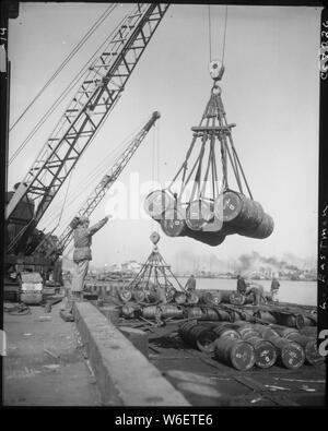 Fuel drums are lifted and moved with cranes from a tanker at Inchon ...