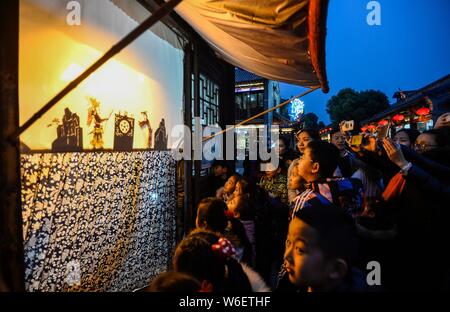 Visitors watch 60-year-old Chinese folk artist Chen Shouke performing shadow play or shadow puppetry, also known as shadow puppet, in Tai'erzhuang dis Stock Photo