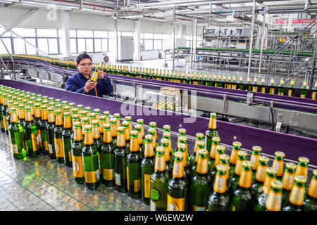 --FILE--A Chinese worker checks beer on a production line at a brewery ...