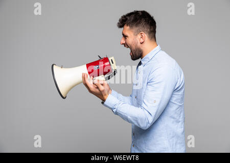 Side view of angry man shouting through megaphone against white background Stock Photo
