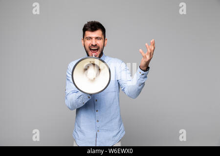Side view of angry man shouting through megaphone against white background Stock Photo