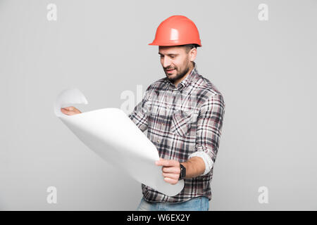 Male Caucasian construction engineer looking at blueprints while wearing formal suit and helmet, isolated on white background Stock Photo