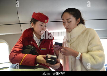 --FILE--A passenger uses her smartphone to scan the QR code to pay her ticket on a train from Hohhot to Beijing in north China's Inner Mongolia Autono Stock Photo