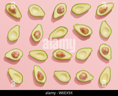 Avocados cut in halves on pink background, set of avocado flat lay Stock Photo