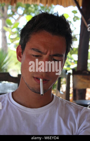 Young man looking concentrated with an unlit cigarette in his mouth Stock Photo
