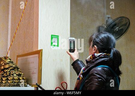 --FILE--A customer uses her smartphone to scan the QR code of WeChat Payment of the messaging app Weixin, or WeChat, of Tencent to pay her purchase in Stock Photo