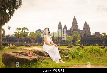 Emancipated Asian solo woman traveler exploring the temple of Angkor Wat, Siem Reap, Cambodia in white dress Stock Photo