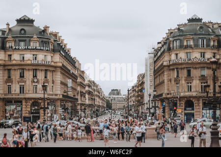 PARIS, FRANCE - JULY 19th, 2014. A view down Avenue de l'Opera busy with pedestrians and traffic on a summer day with high clouds.