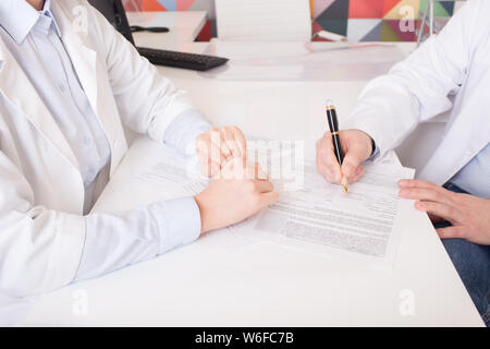 two doctors in gowns, sign documents Stock Photo
