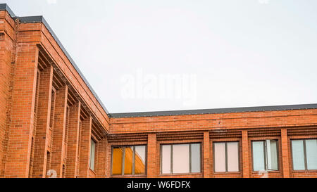 Panorama Exterior of red brick building with flat rooftop and shiny sliding windows Stock Photo