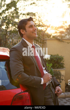 Businessman holding white rose and smiling Stock Photo