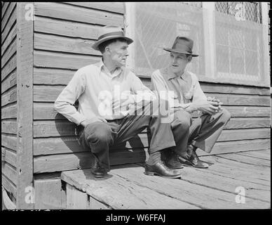 Blaine Sergent, left, talks with a fellow miner in the front porch of the company store on Saturday morning. Talking and visiting was not only the major recreaton of Mr. Sergent, but was one in which he took the greatest pleasure. P V & K Coal Company, Clover Gap Mine, Lejunior, Harlan County, Kentucky. Stock Photo