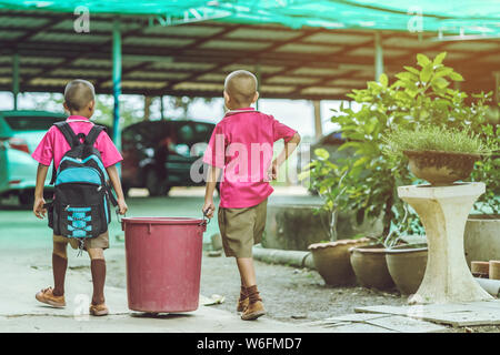 Male Students help to remove rubbish from the classroom to pile waste Stock Photo