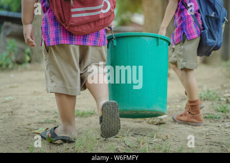 Male Students help to remove rubbish from the classroom to pile waste Stock Photo