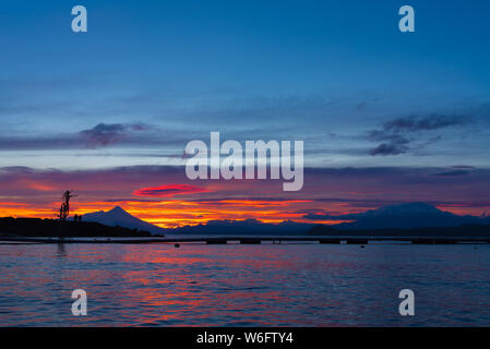 Wide shot of beautiful sunrise colors on the shore of Lake Llanquihue with iconic volcanoes in the background Stock Photo