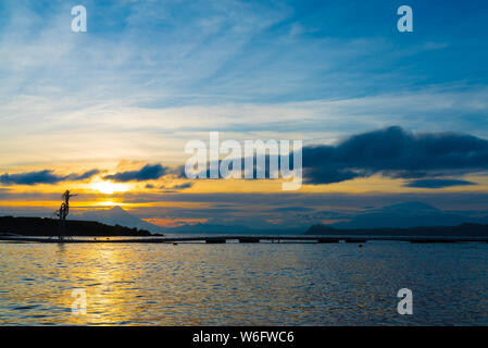Wide shot of beautiful sunrise colors on the shore of Lake Llanquihue with iconic volcanoes in the background Stock Photo
