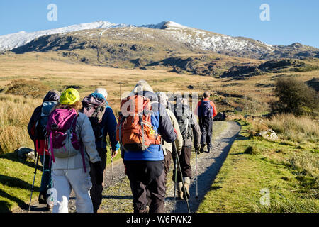 Ramblers group hiking on Rhyd-Ddu path to snow covered Mt Snowdon peak in mountains of Snowdonia National Park. Rhyd-Ddu Gwynedd Wales UK Stock Photo
