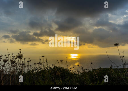 Greece, Zakynthos, Dramatic dark cloudy sky breakthrough of sunrays reflecting on ocean water Stock Photo