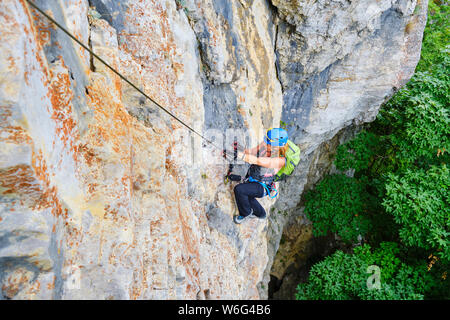 Woman climber on a via ferrata route called Dragons Amphitheater (Amfiteatrul Zmeilor) in Baia de Fier, Gorj county, Romania, near Womens Cave (Pester Stock Photo
