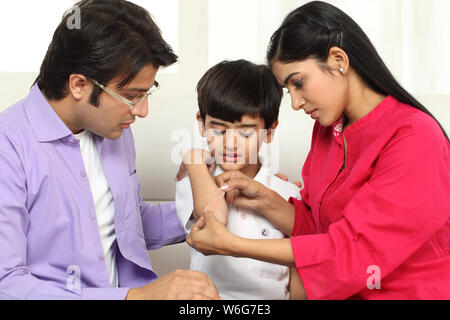 Mother putting bandage on son,s elbow Stock Photo