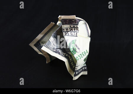 Crumpled one hundred American dollar on black paper background, close-up of bad money. The collapse of the dollar. Devaluation. Falling currency. Stock Photo