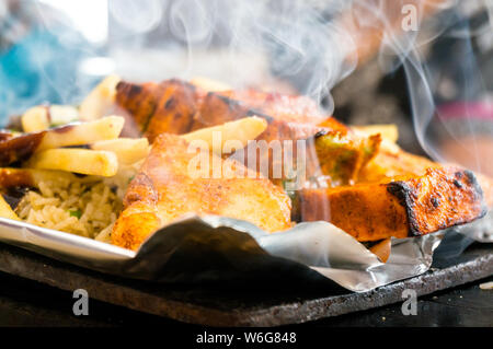 Delicious paneer, french fries and vegetble sizzler giving off smoke and steam Stock Photo