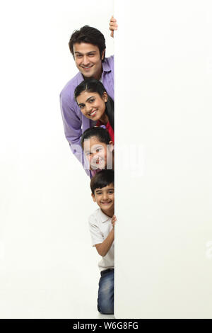 Family hiding behind a wall Stock Photo